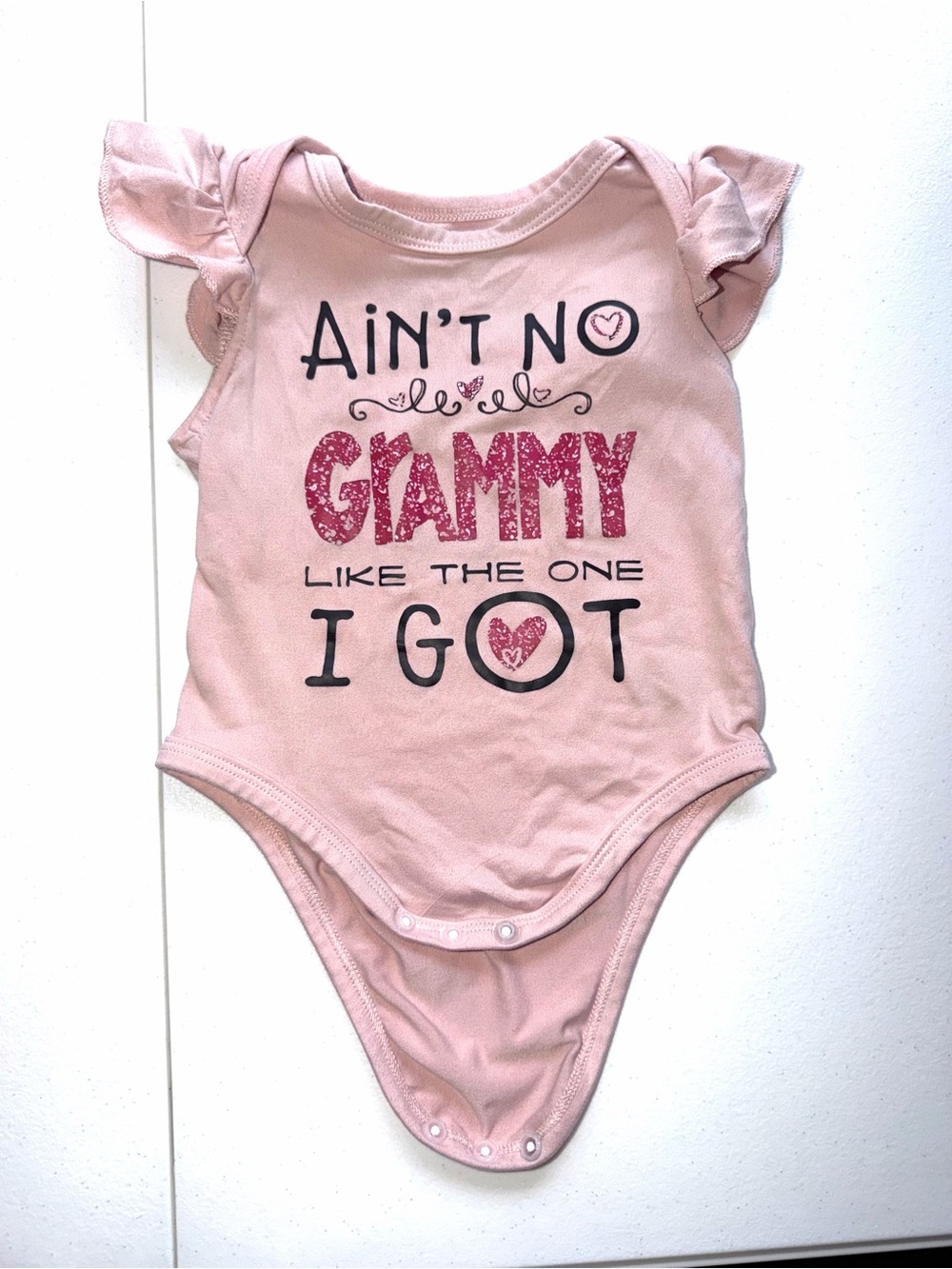 Pink baby onesie with glittery text reading 'Ain't no Grammy like the one I got'